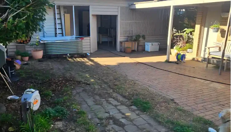 Before photo of a cluttered backyard with scattered gardening tools, pots, and overgrown plants, ideal for showcasing outdoor cleaning and yard maintenance services.