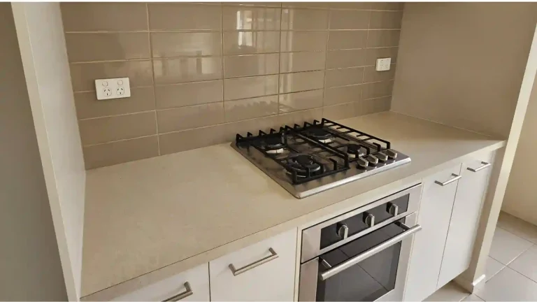 re-renovation kitchen featuring built-in gas stove, oven, white cabinetry, and beige tile backsplash with a baseline setup before modern upgrade.