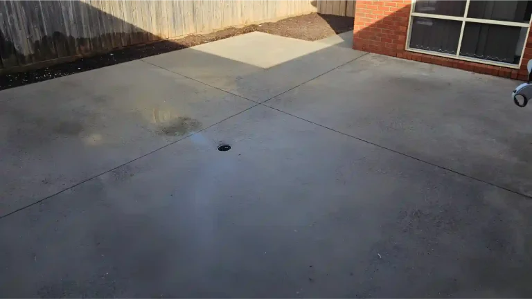 Melbourne Property Preparers after photo of clean concrete patio in Melbourne with central drain and neat garden edging following outdoor pressure washing for improved property presentation