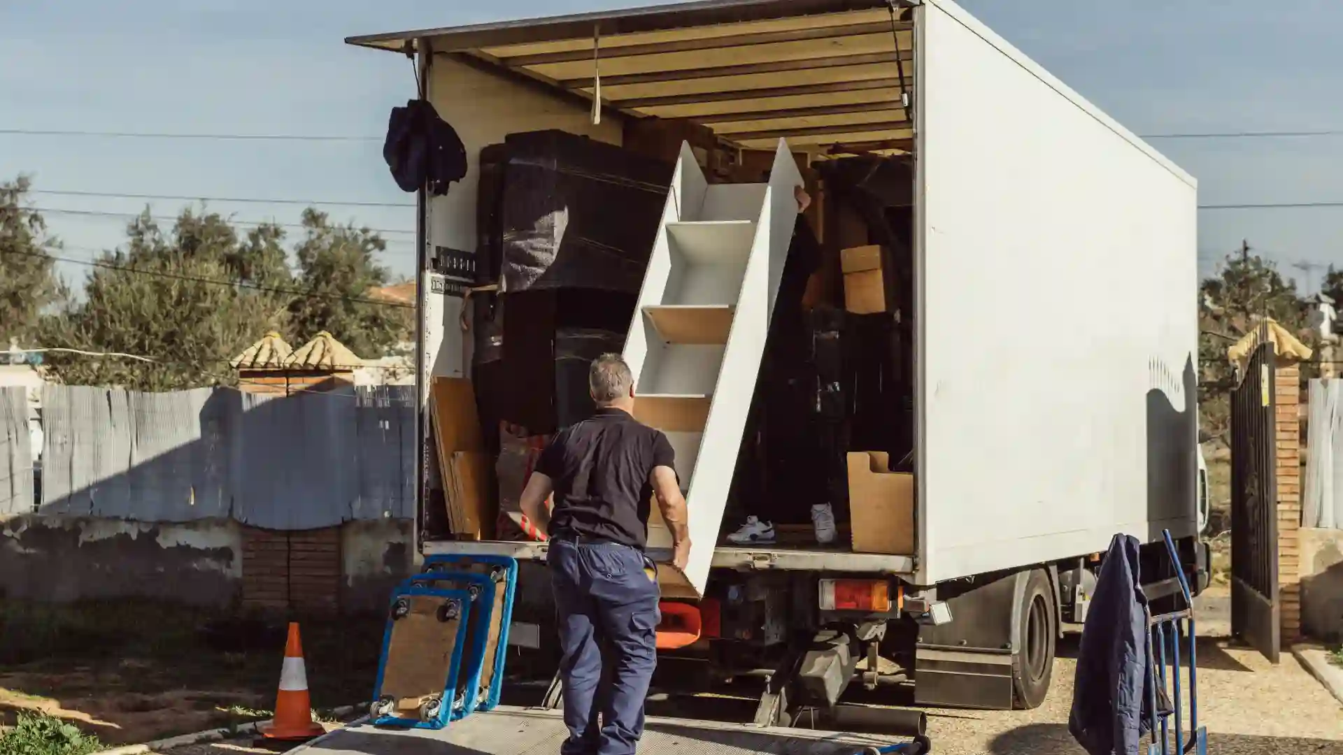 Rubbish removal in progress with a worker loading household items including furniture and boxes into a large truck. Professional clean-up and disposal service for residential properties in Australia.