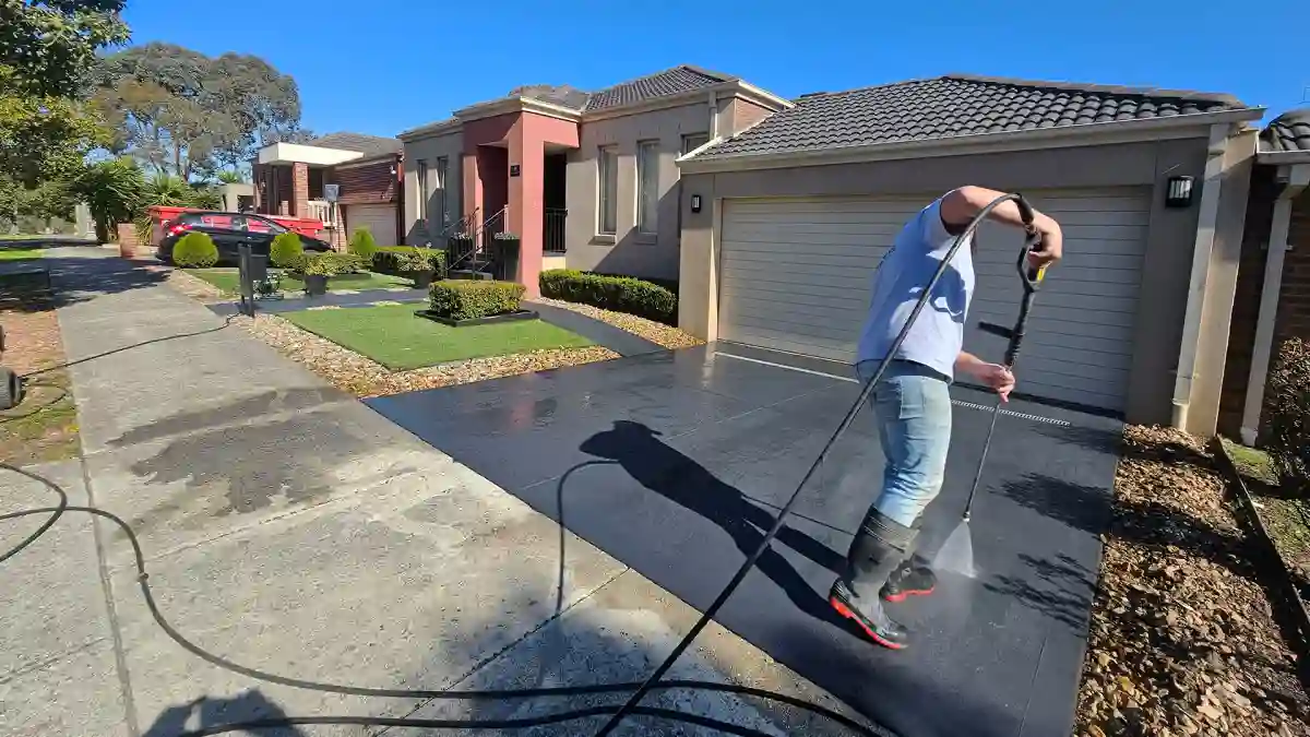 Melbourne Property Preparers team member pressure washing dark coloured driveway in Melbourne to remove dirt and stains and improve curb appeal during residential property maintenance