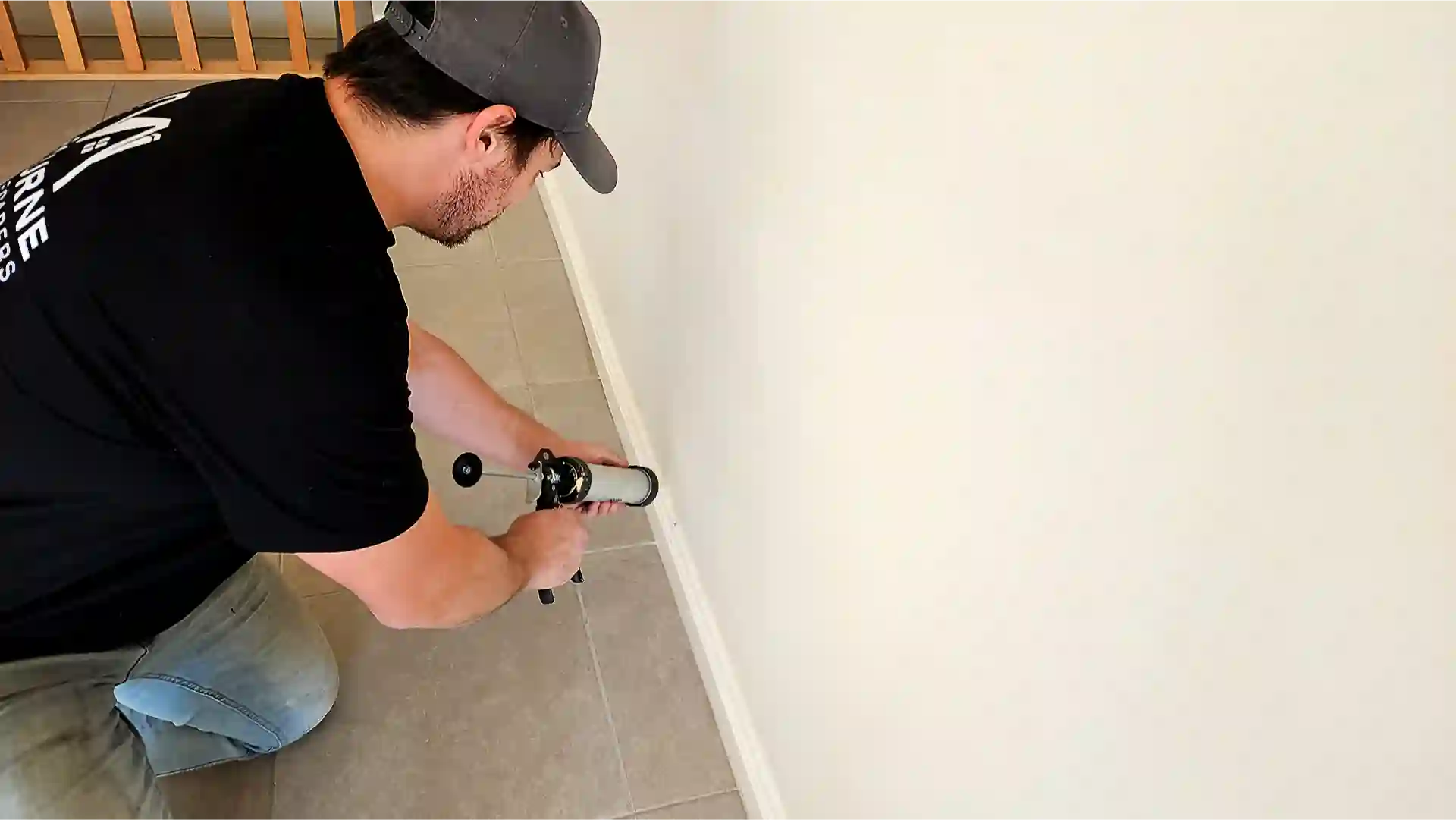 Melbourne Property Preparers team member applying caulk along baseboard with caulking gun during interior property maintenance in Melbourne sealing gaps to improve appearance and prevent drafts or moisture entry